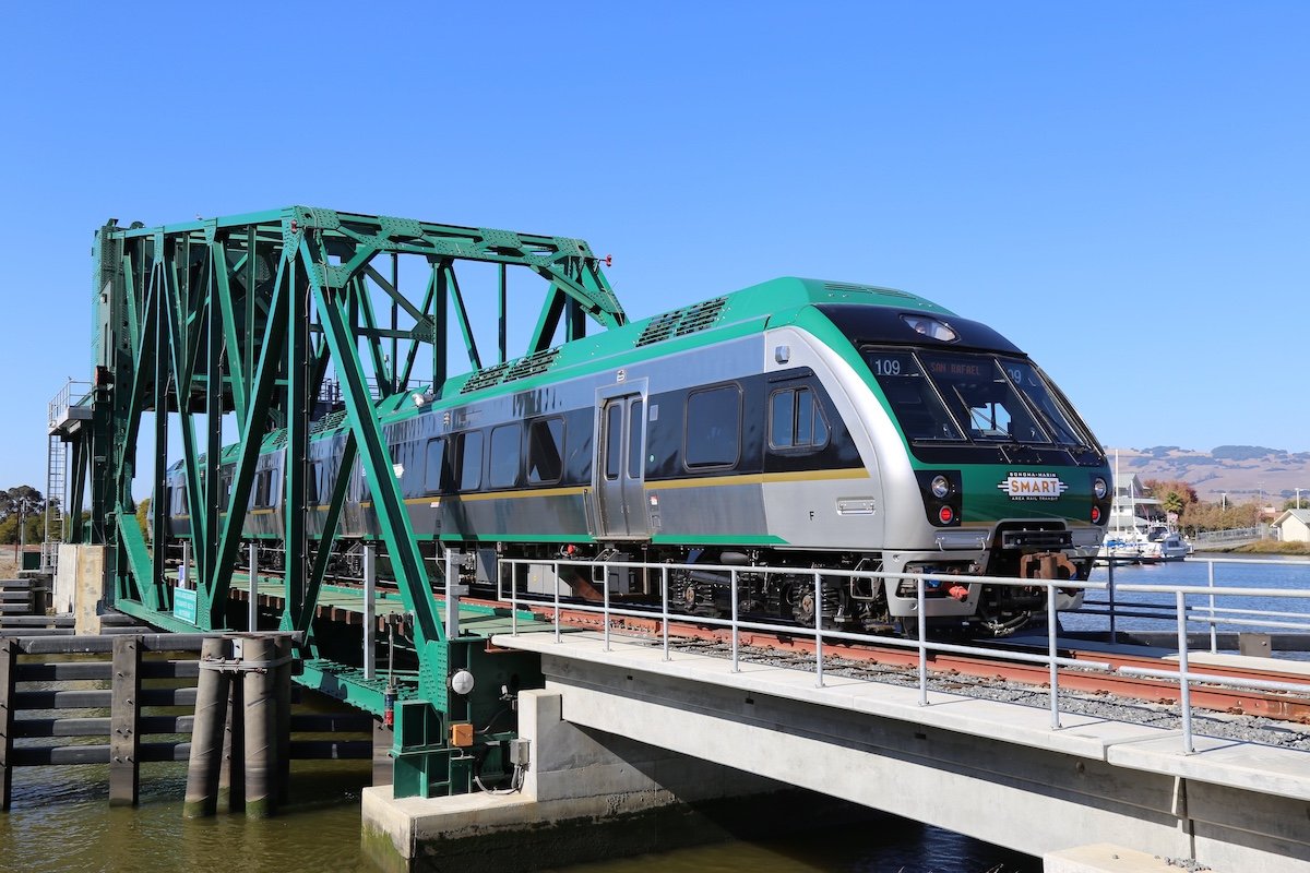 green train crossing bridge