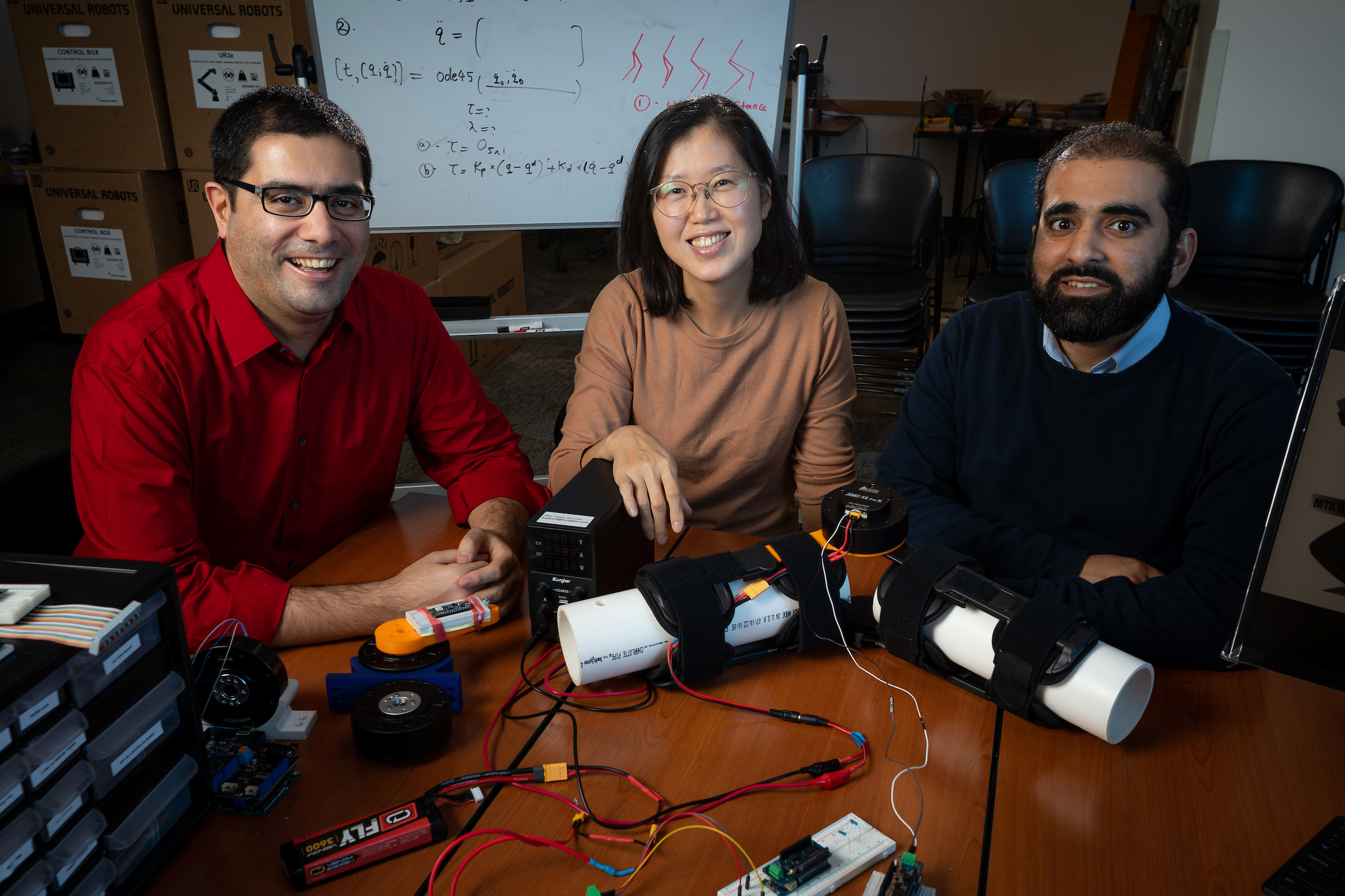 Three faculty at table with robotics elements and a map