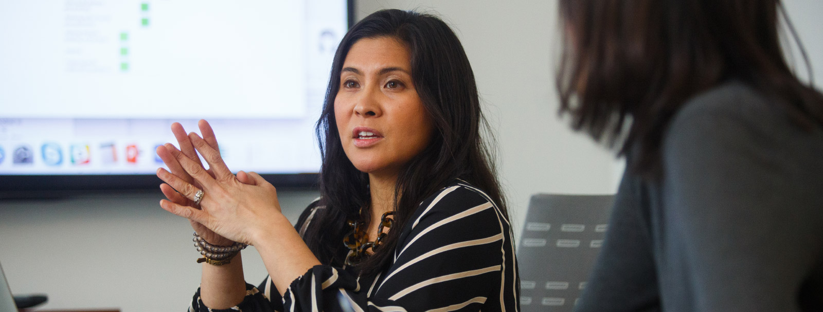 Woman of east Asian heritage talking near a projected display