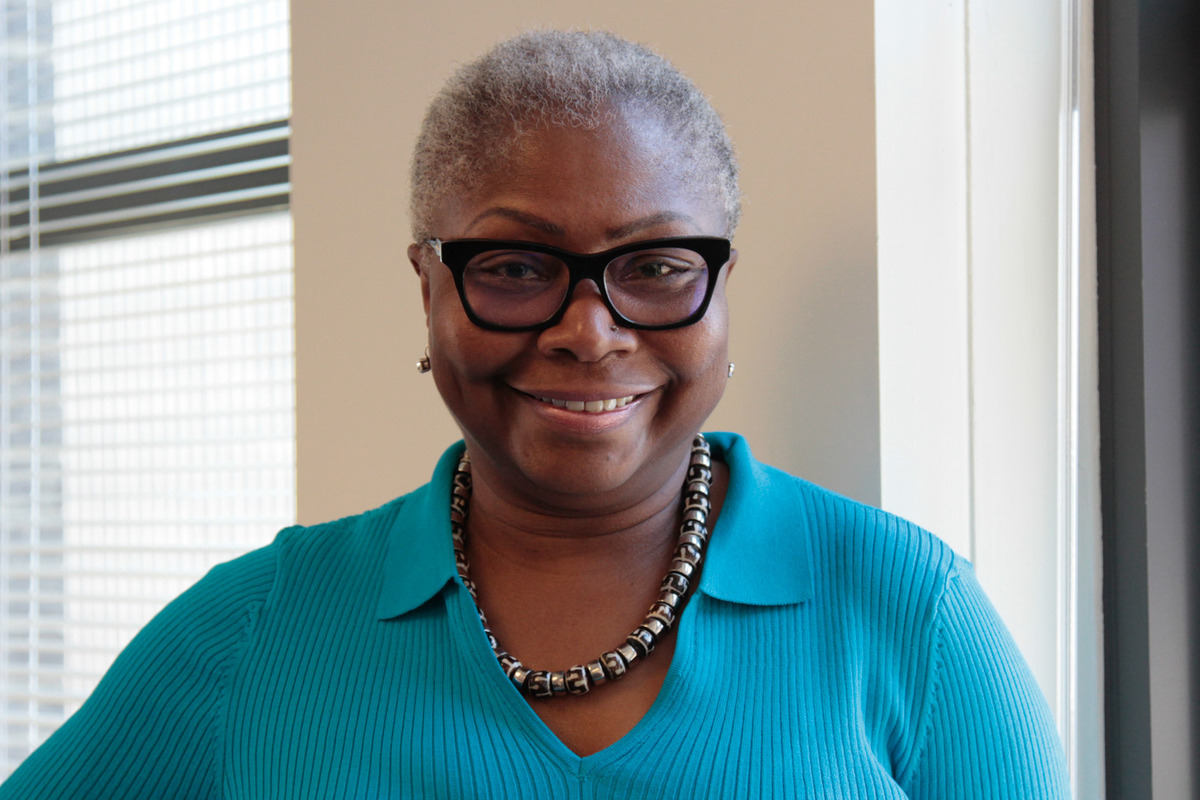 Valerie Johnson poses by a window wearing a neon blue shirt
